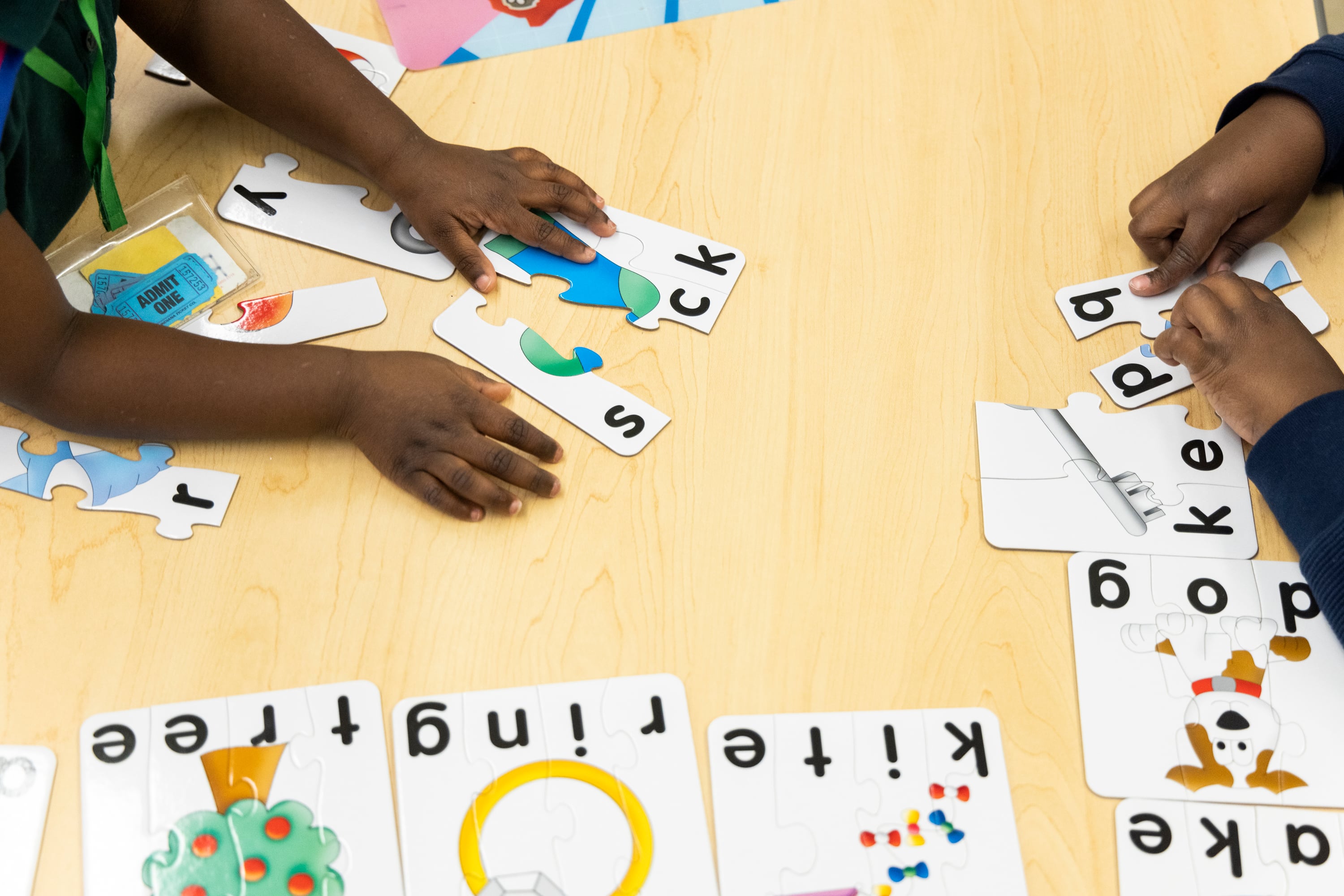 A close-up of children’s hands as they work on word puzzles.