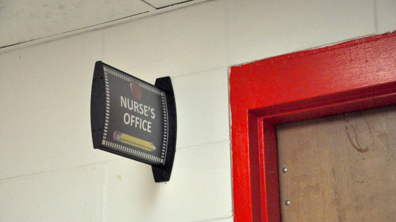 A sign in a school hallway that reads "Nurses' Office" next to a red door.