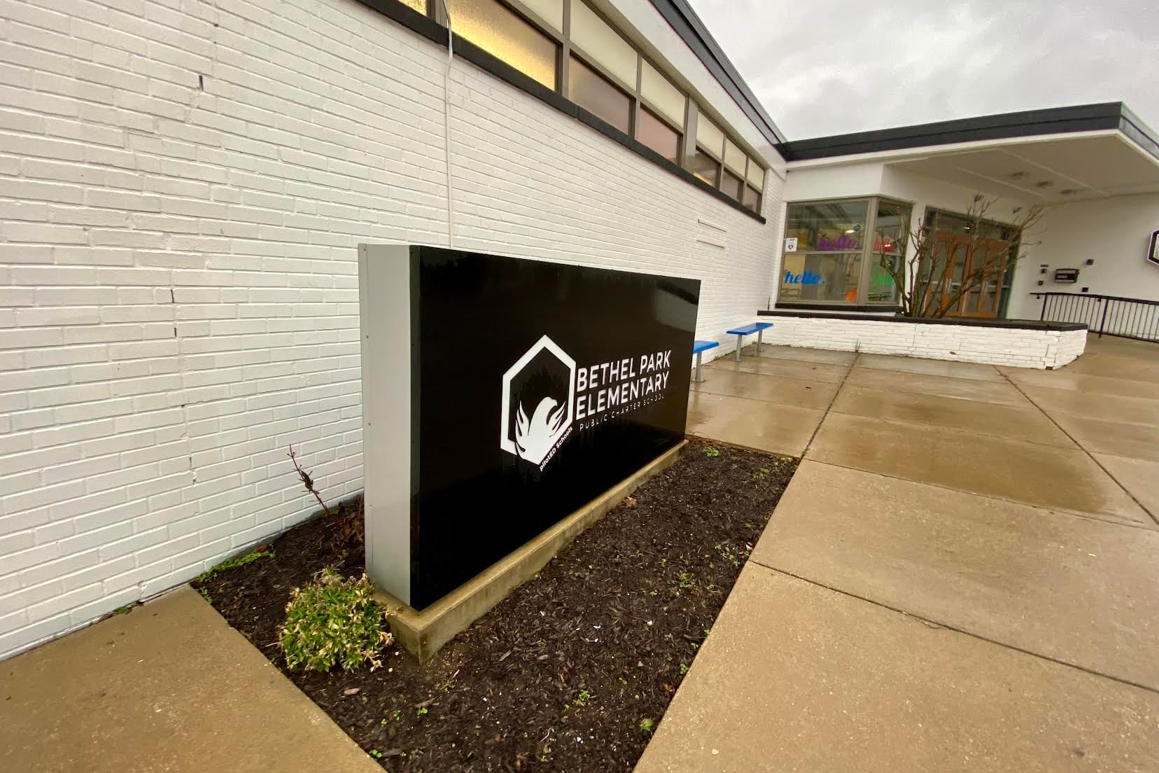 building sign outside of a white brick building on a cloudy day.