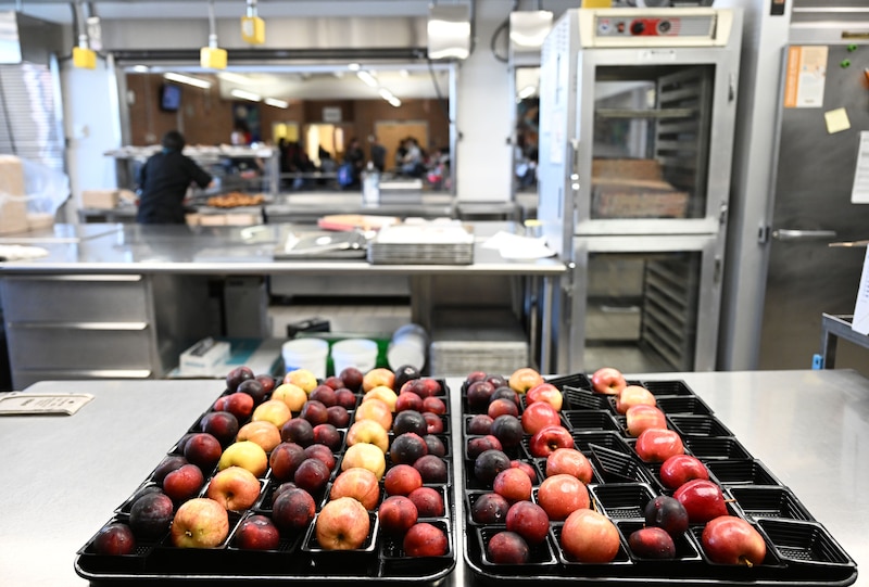 A tray of fruit sit on a school cafeteria in the foreground.
