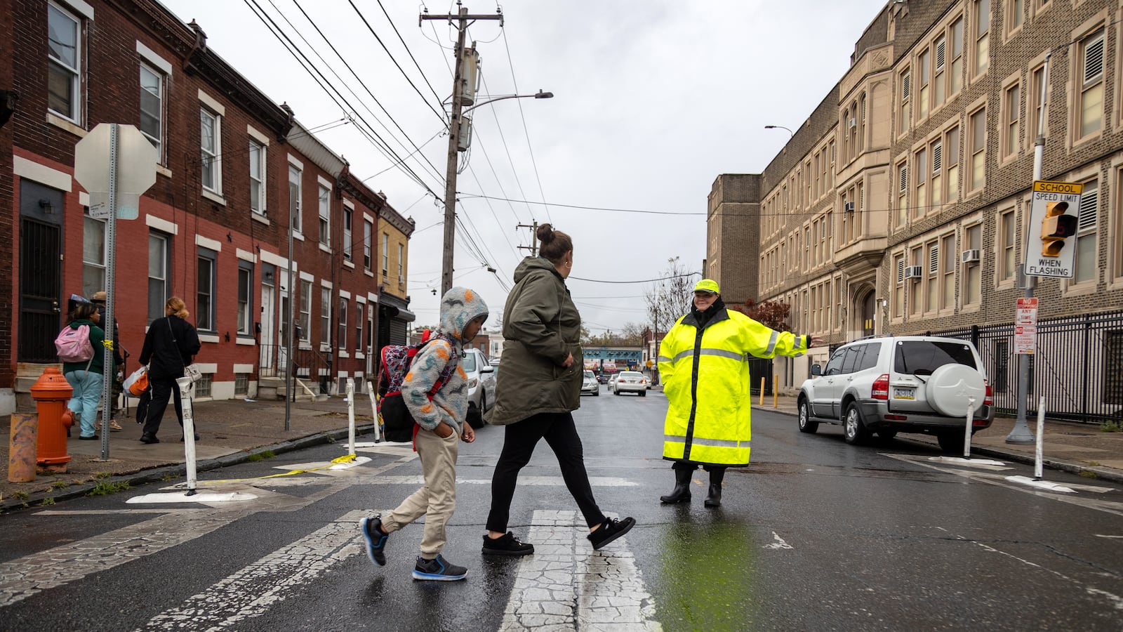 People cross the street in front of a crossing guard.