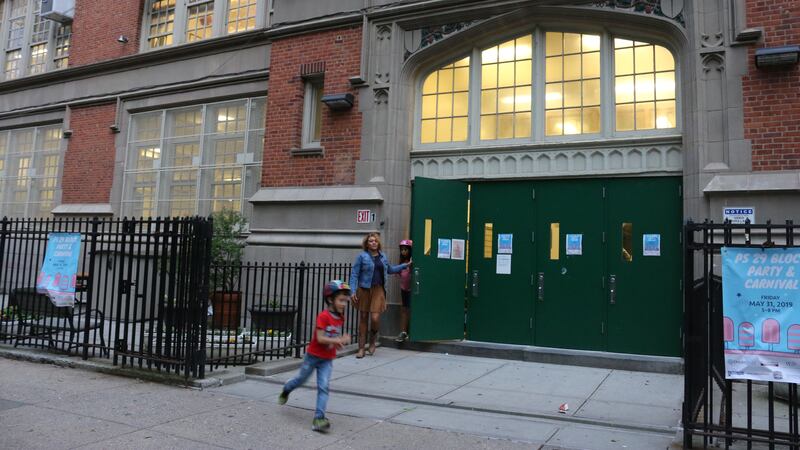 The outside front doors of P.S. 29 in Cobble Hill are pictured, with a child out front. The school is one of seven schools that could be affected by sweeping attendance zone changes proposed for Brooklyn’s District 15.