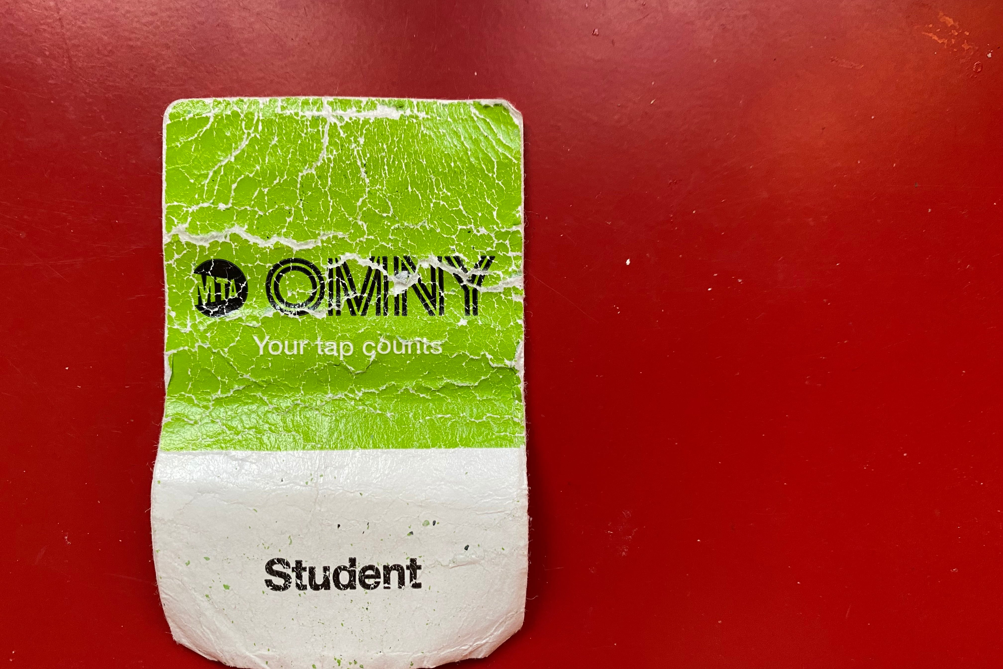 A close up of a green, white and black paper ticket on a red table.