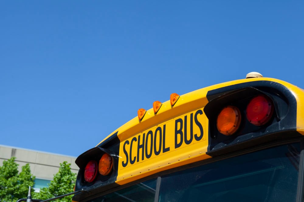 A portion of the back side of a school bus with a blue sky in the background.