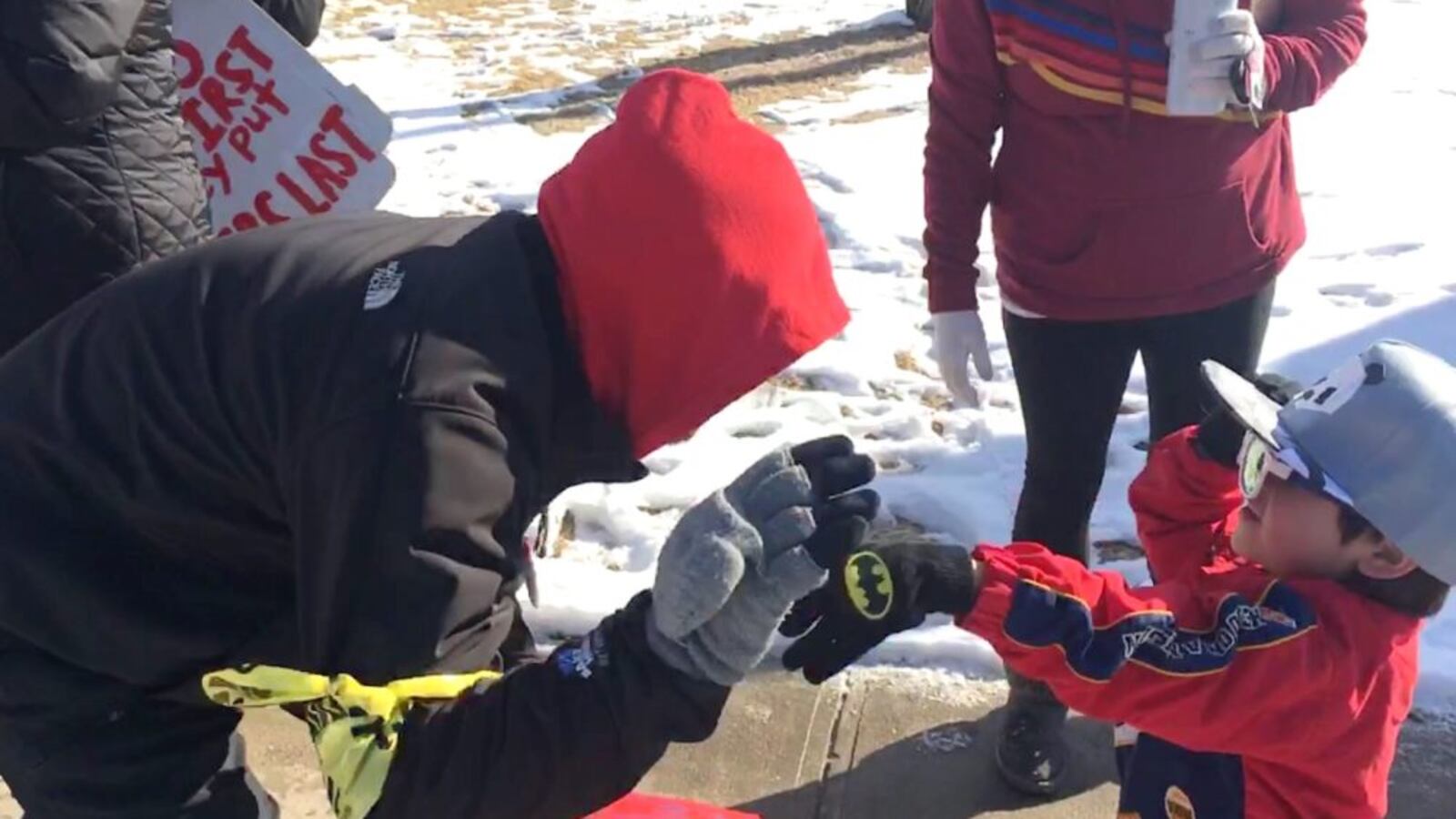 A Denver preschooler gives a striker a high five while walking the picket line with his mother, a Denver teacher.