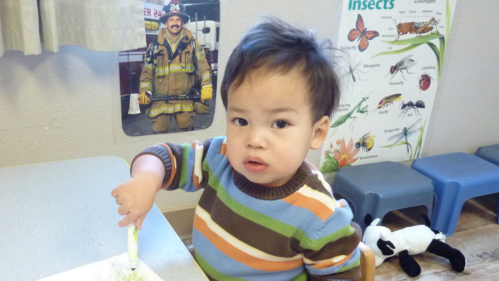 A toddler at Loveland's Teaching Tree  Early Childhood Learning Center, draws on an outline of his foot.