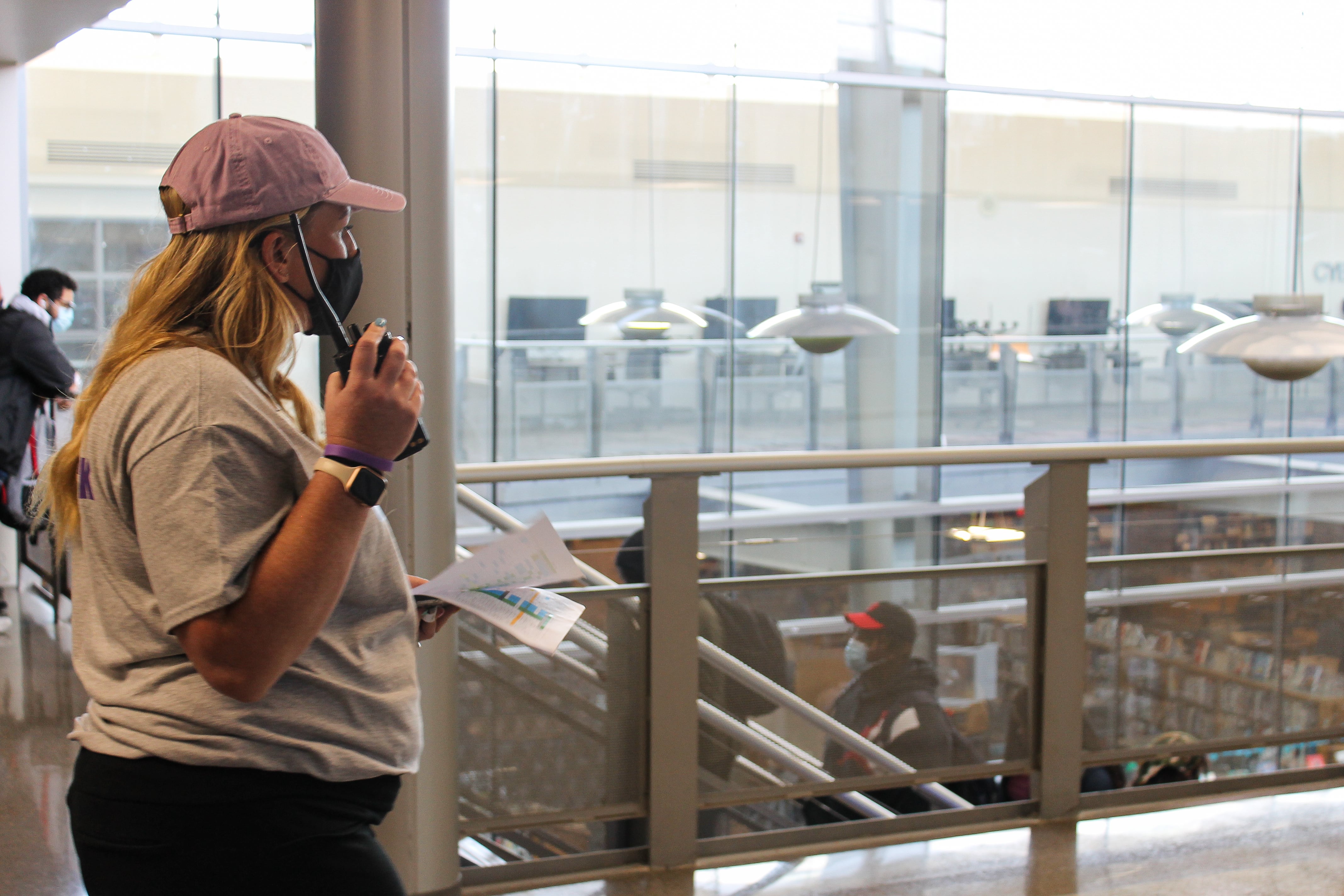 A woman wearing a mauve baseball cap and carrying a walkie-talkie stands near the top of the stairs at Ben Davis High School in Indianapolis, Ind., last spring when schools in Wayne Township returned to full-time in-person learning.