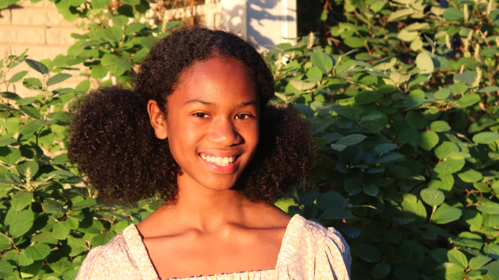 Headshot of a teenage girl wearing a white shirt. Her hair is in pigtails.