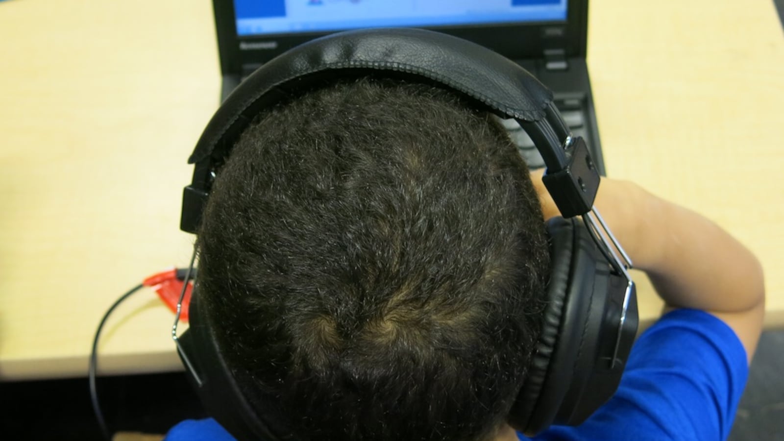 A young student wearing headphones and working on a laptop.