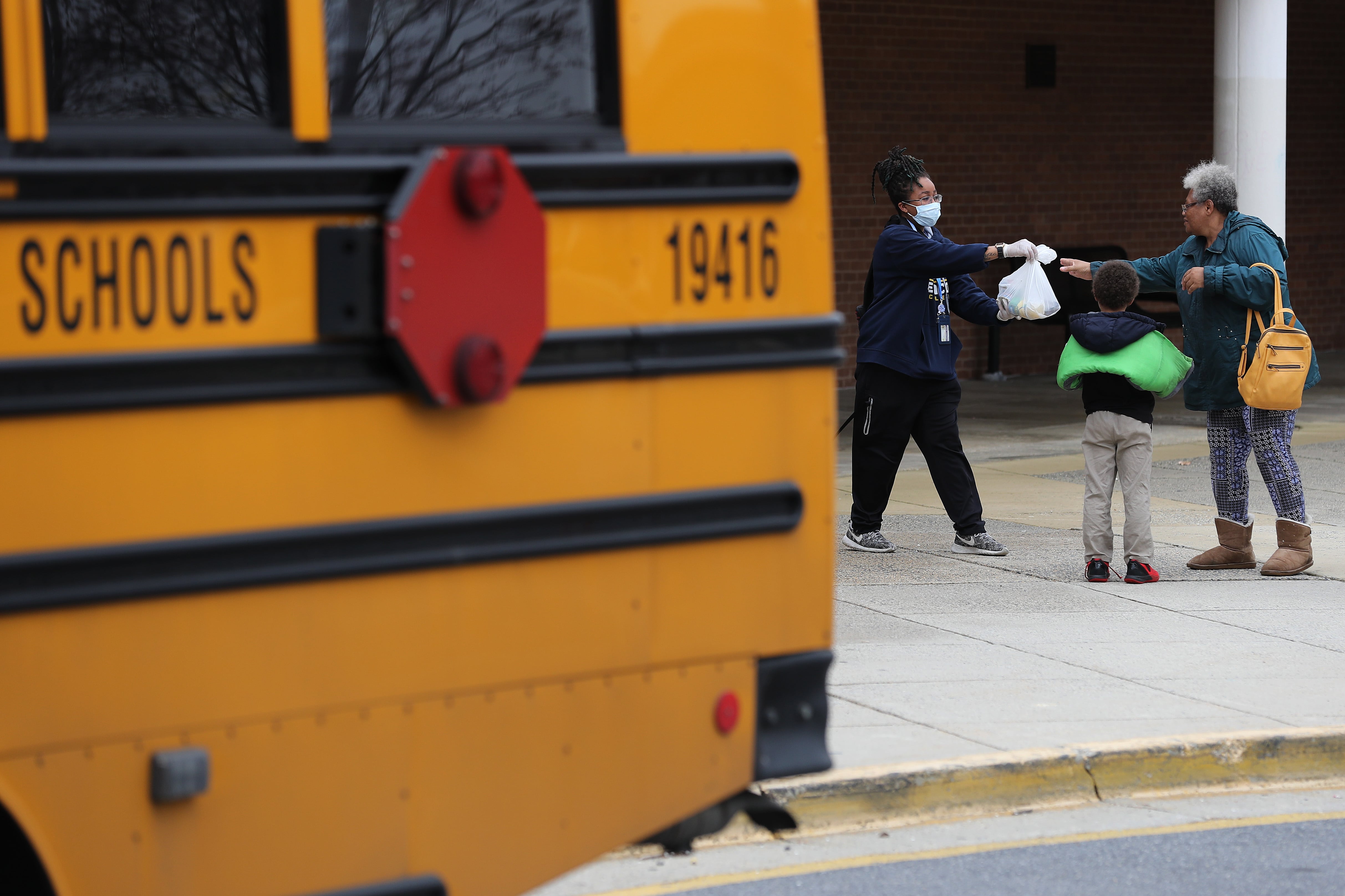 GAITHERSBURG, MARYLAND - MARCH 20: Montgomery County Public Schools Special Needs Bus Attendant Zanashia Rowe helps distribute bags of food donated by Manna Food Center at Quince Orchard High School as part of a program to feed children while schools are closed due to the coronavirus March 20, 2020 in Gaithersburg, Maryland. Millions of children across the country rely on meals they get at school, which are closed in an attempt to suppress transmission of the COVID-19 virus.