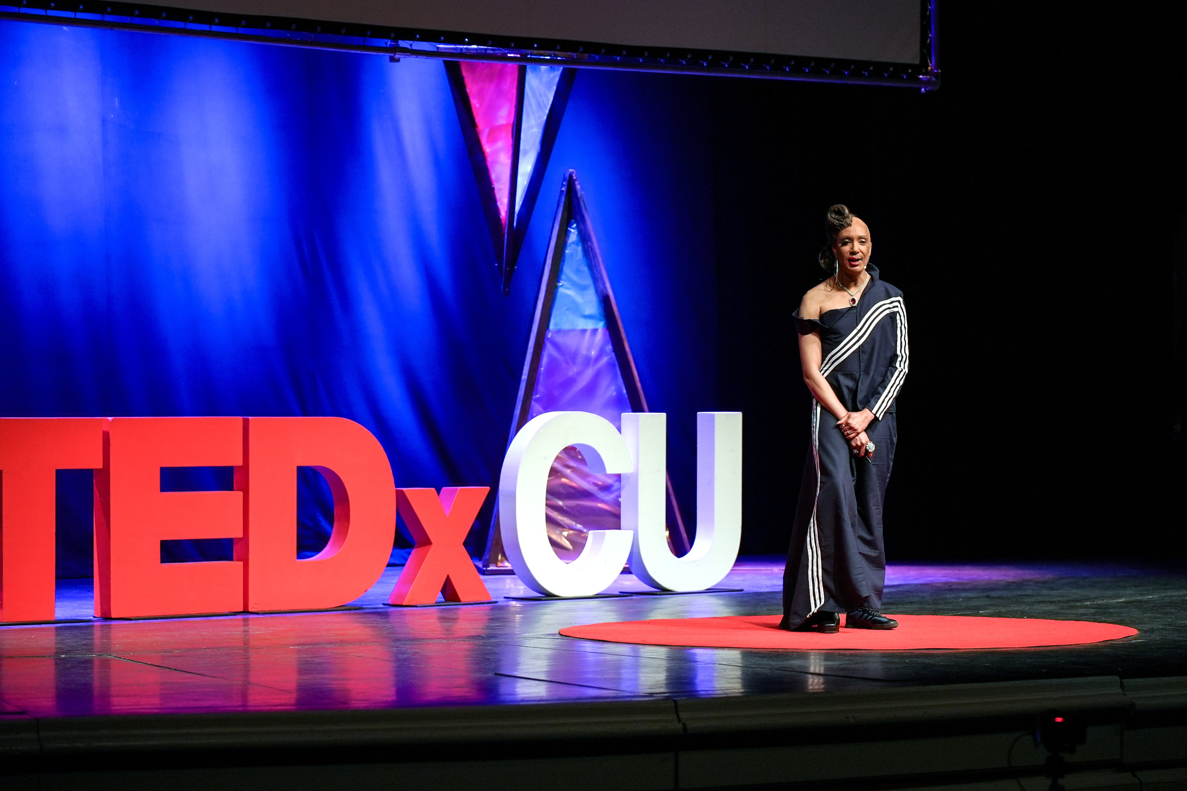 A person stands on a stage in front of large type.