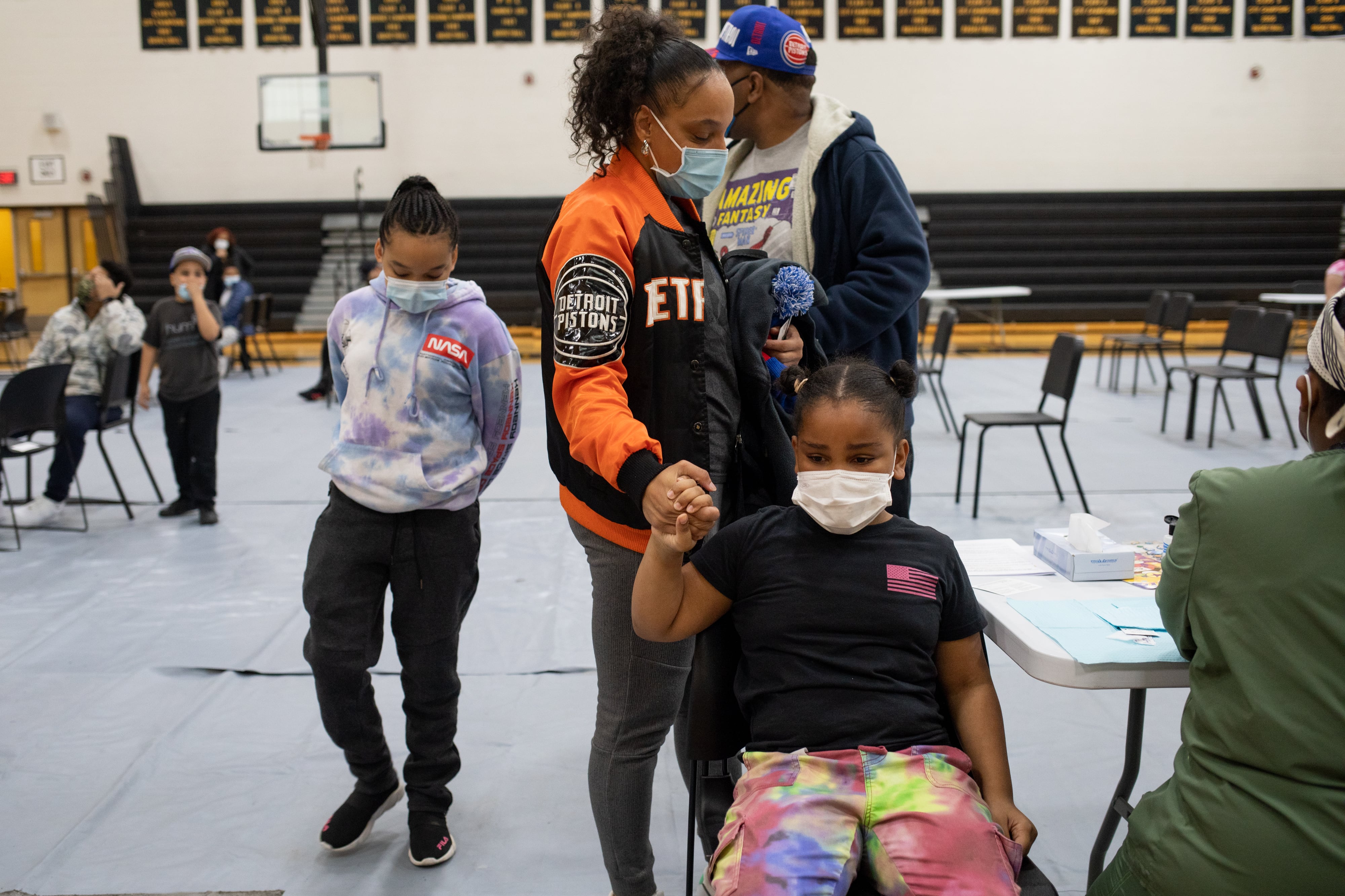 A girl holds her mother’s hand as she gets ready to receive her first dose of the Pfizer-BioNTech coronavirus disease (COVID-19) vaccine during a pediatric vaccine clinic at Martin Luther King, Jr. Senior High School in Detroit, Michigan,
