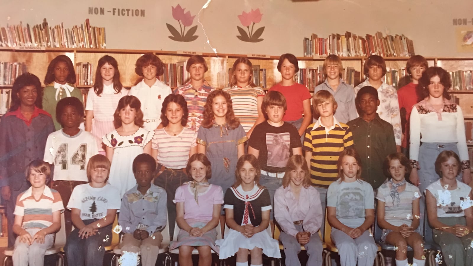 The integrated sixth grade class at Raleigh Bartlett-Meadows in the mid-1970s. Jacqueline Hill-Ferby, who was bused to the school from her home 45 minutes away, is standing on the far left, wearing green, behind one of her first professional role models and teacher, Mrs. Glover. Hill-Ferby, who became a teacher herself, says busing was a positive experience for her.