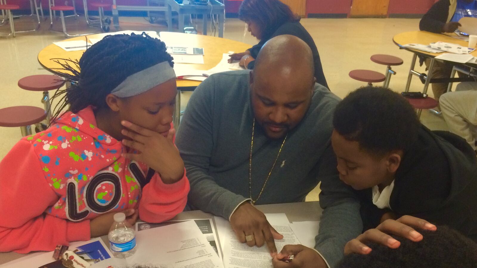 Shamaine Walls reviews TNReady practice questions with his niece Angelica Walls and nephew Mario Taylor at a TNReady information event sponsored in Memphis by the Tennessee Education Association.