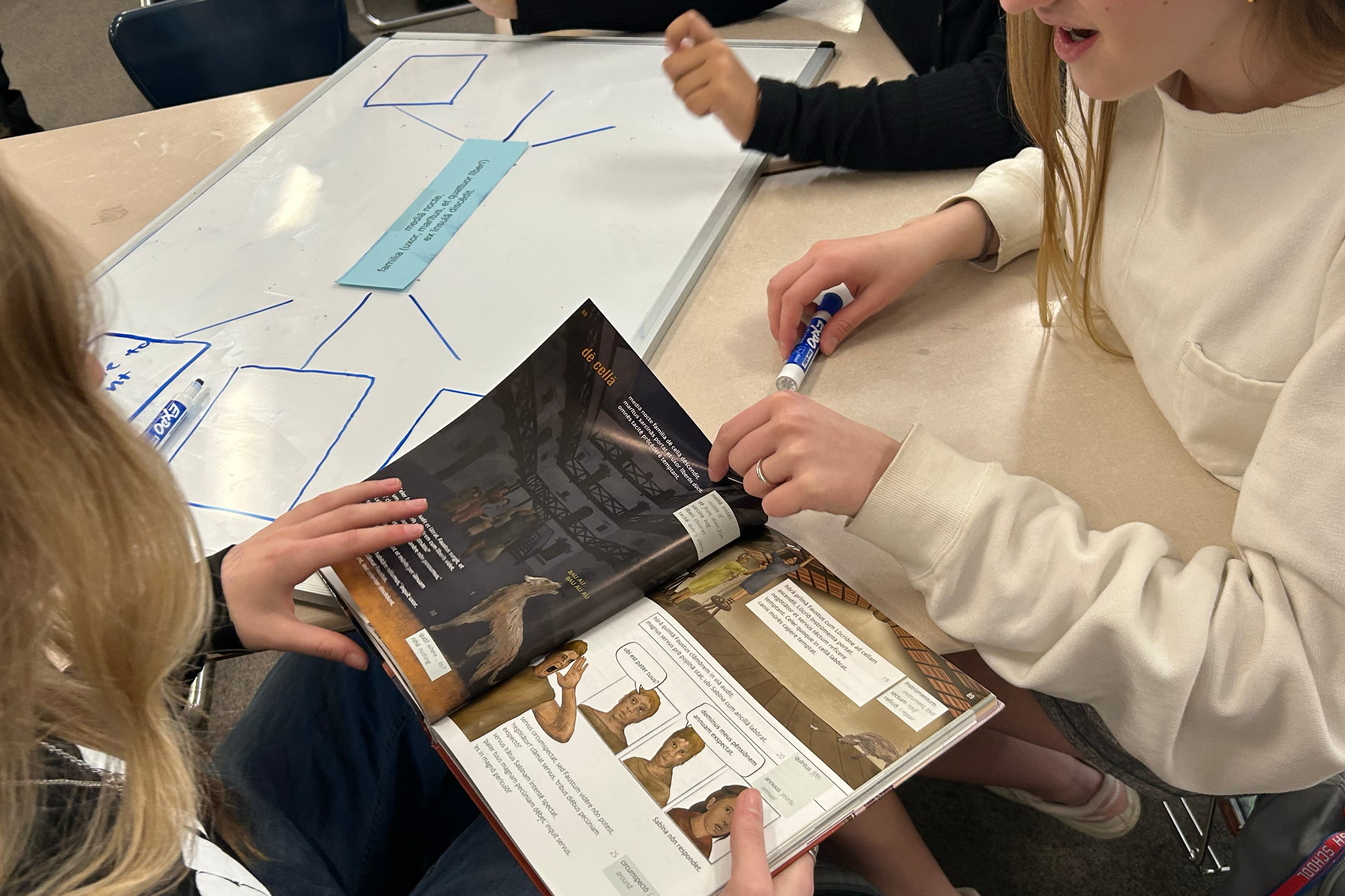 Two high school students sit at desks working on school work in a classroom.