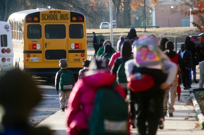 A photograph of students in winter coats walking toward a yellow school bus.
