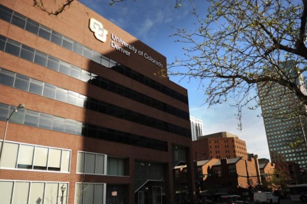 A brown building with windows at the University of Colorado Denver campus against the backdrop of other city buildings and a blue sky.