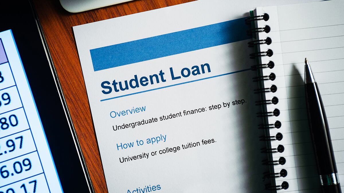 Student loan document on a desk with a pen and pad of paper.