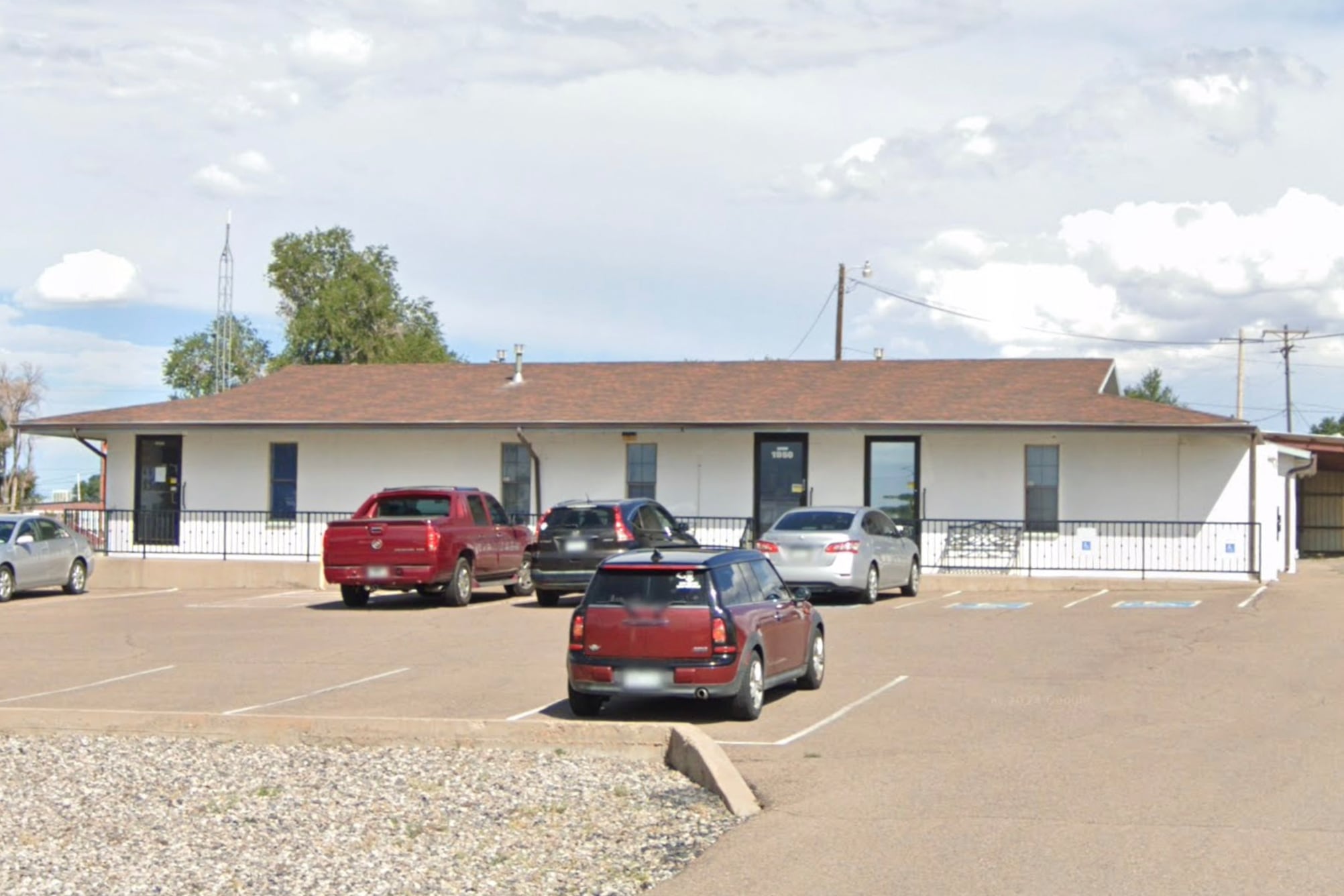 A screen grab of a google maps street view of a school building on a sunny day with cars parked in the parking lot out front.