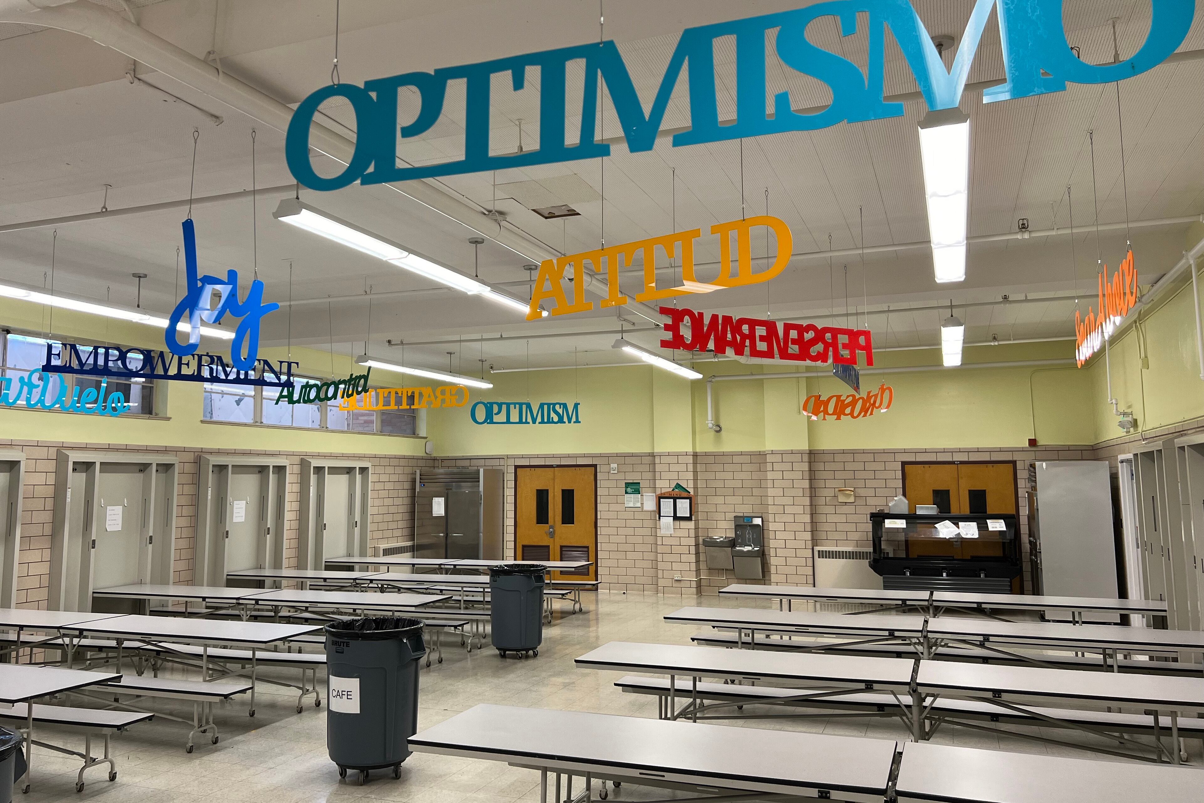 Signs of different words hang from the ceiling of a school cafeteria.