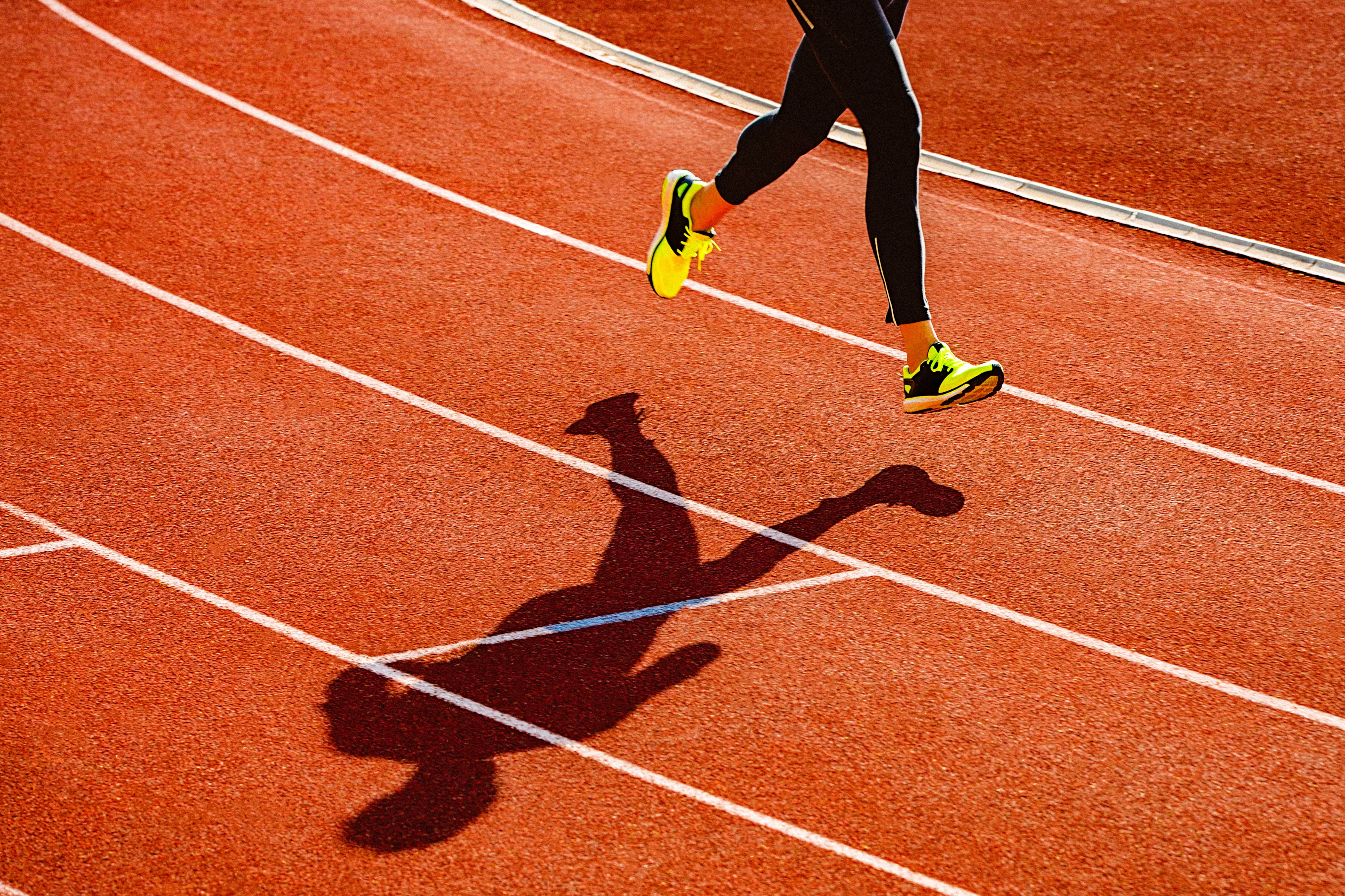 A runner's legs are silhouetted on a track.