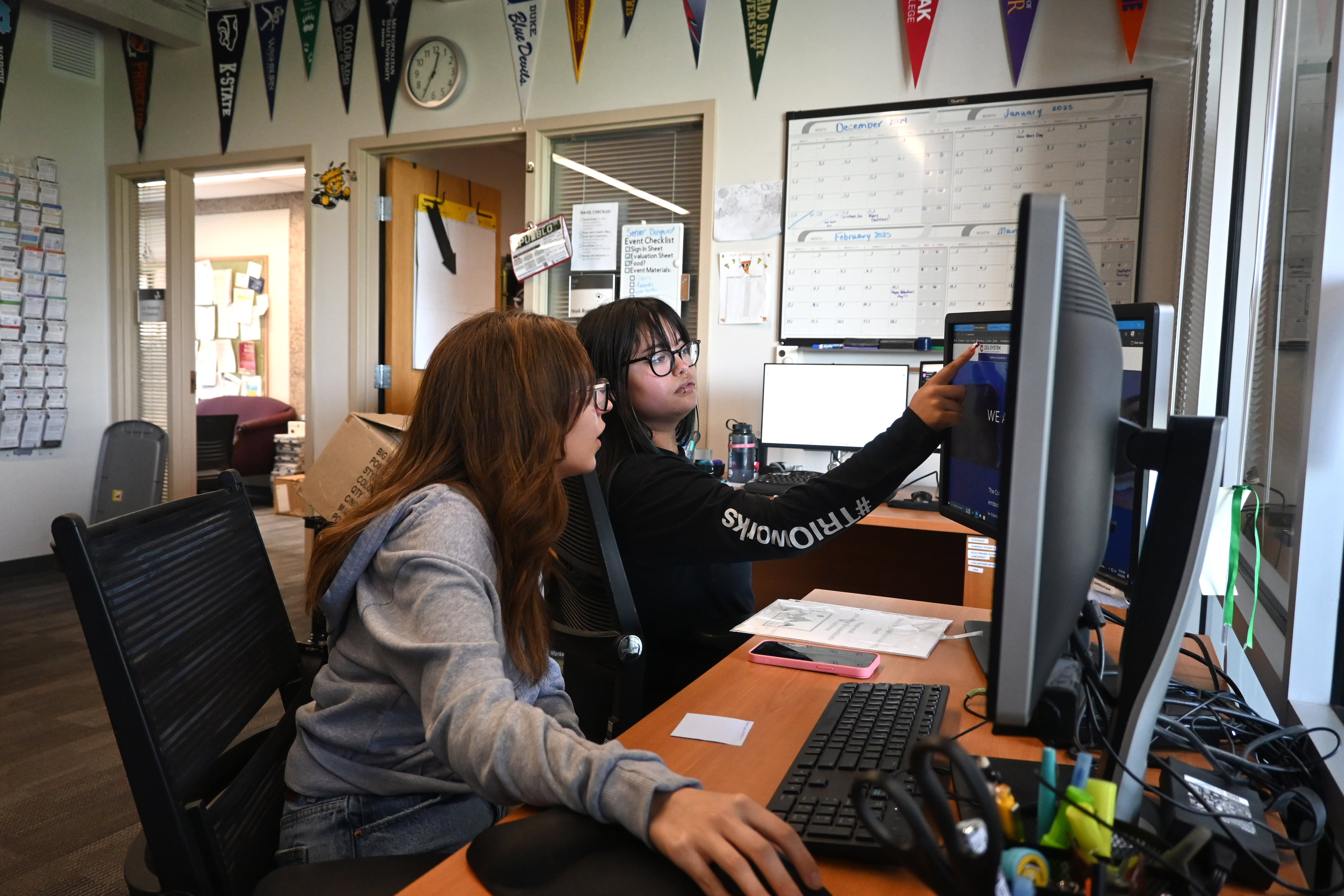 Two female students work at a computer screen.