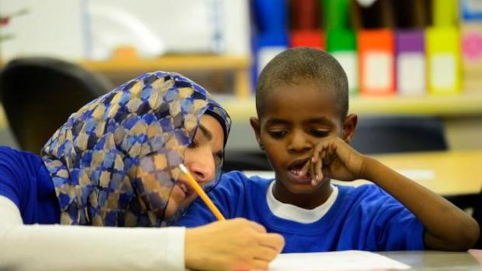 Merhan Zeina, a second-grade teacher at McMeen Elementary in Denver, helps Ahmed Abdelhadi, 8, write a number story.