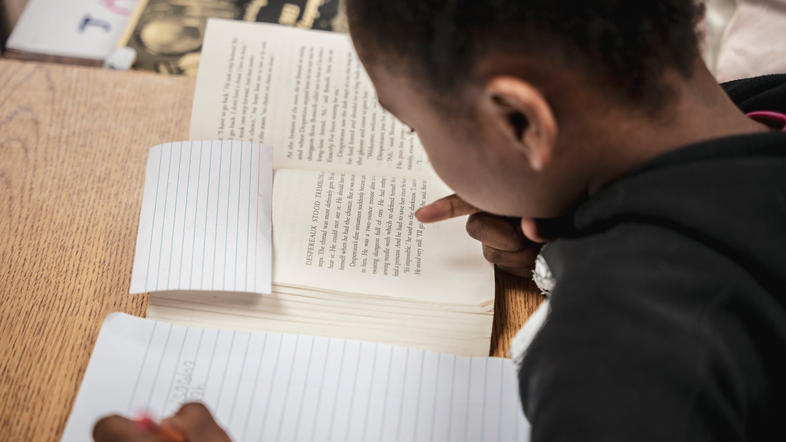 A student looks down and writes in a notebook