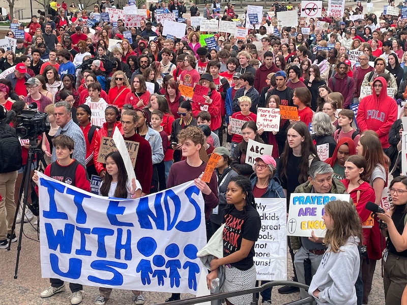 A large group of students carrying signs and banners advocating for limits on guns