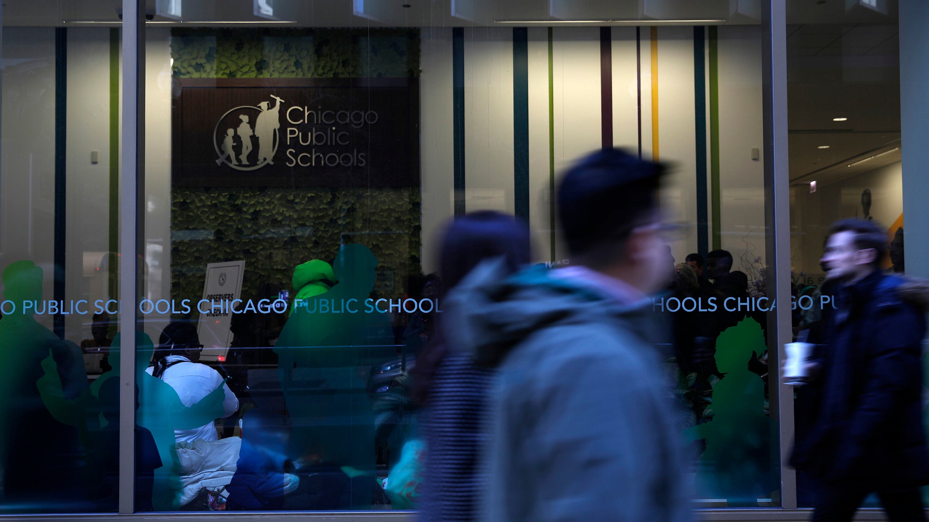 Students walk in front of a glass window at the headquarters of Chicago Public Schools.