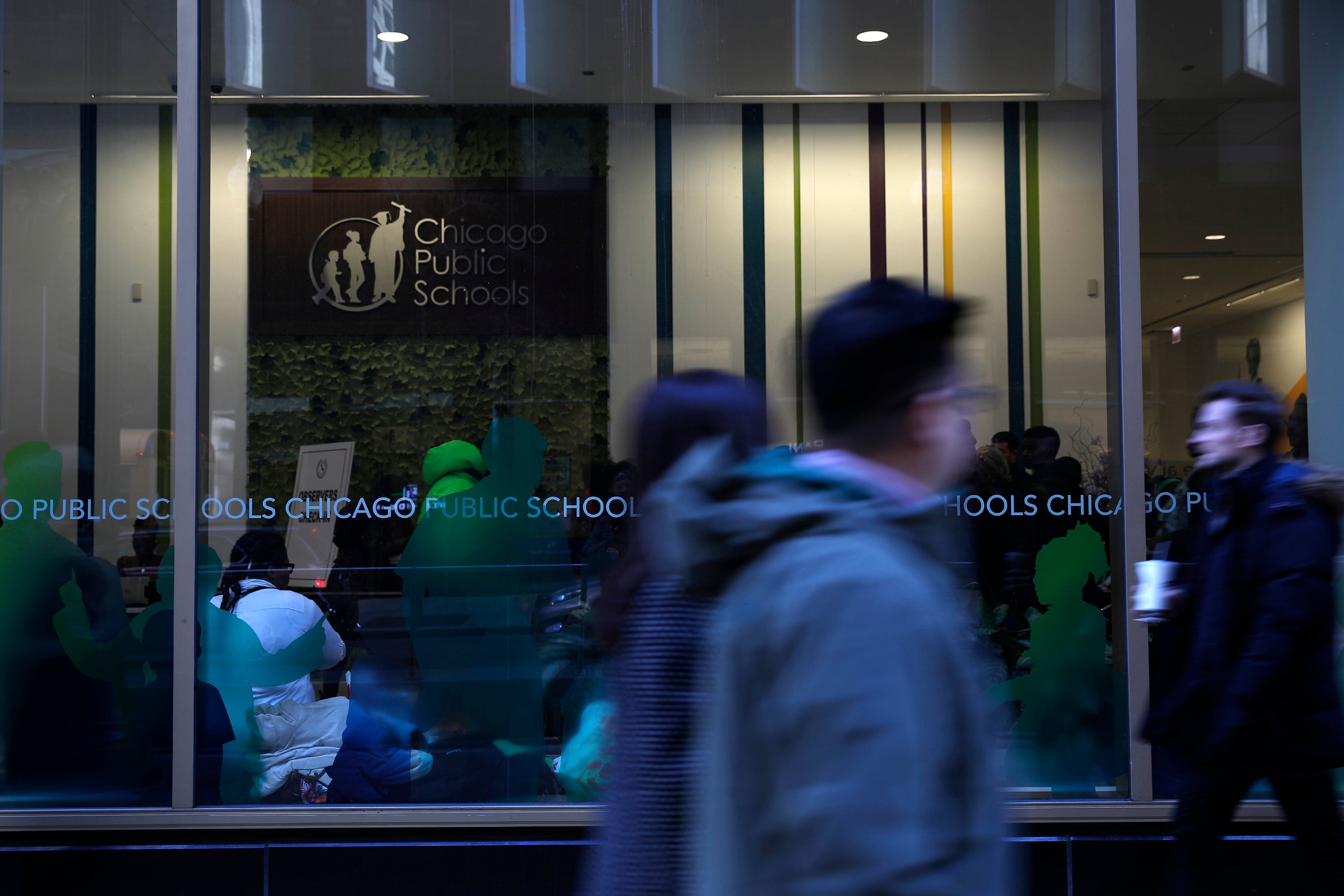 Students walk in front of a glass window at the headquarters of Chicago Public Schools.
