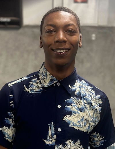 Portrait of a young man wearing a dark blue shirt with tropical pattern, buttoned up.