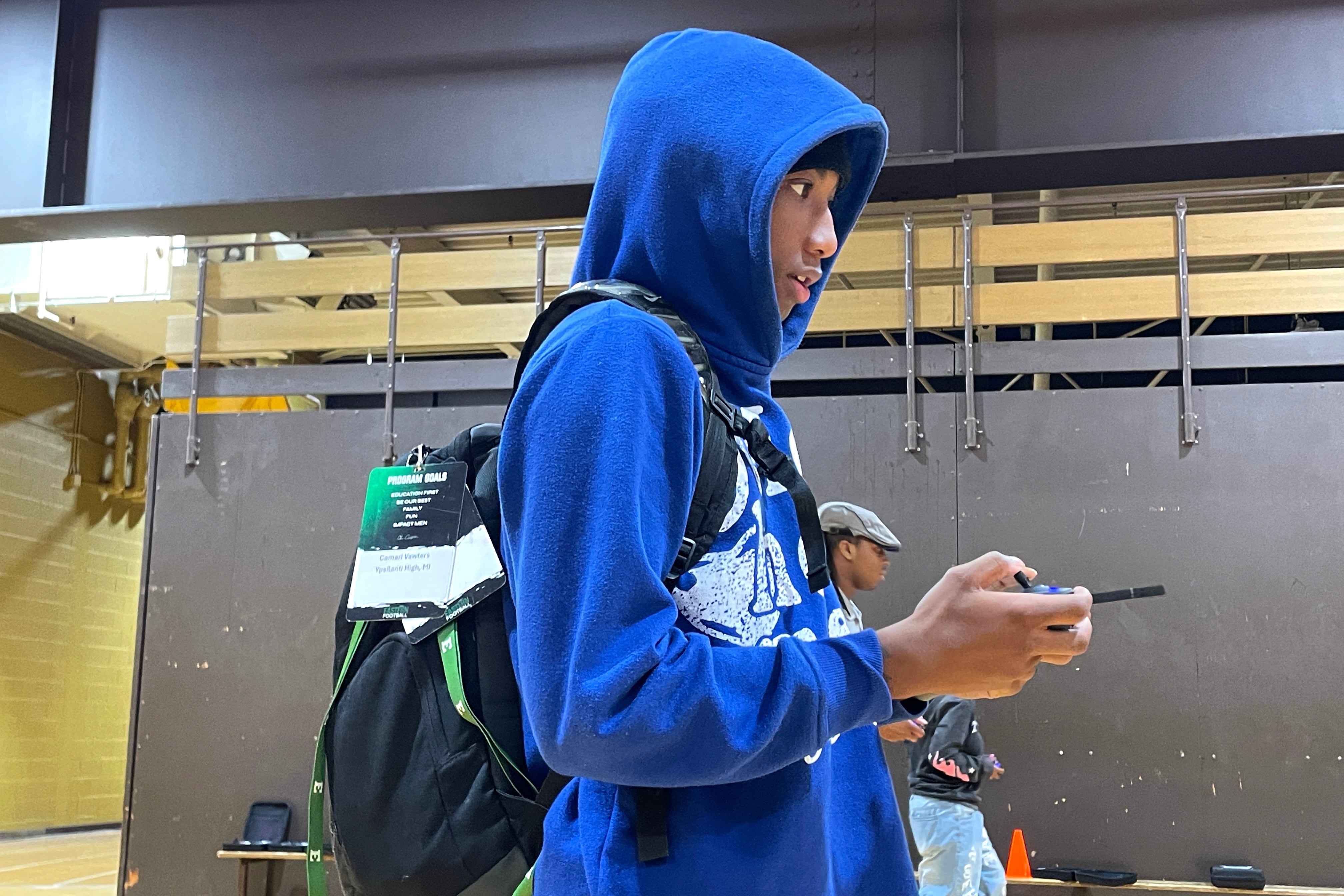 A teen in a blue hoodie holds some equipment.