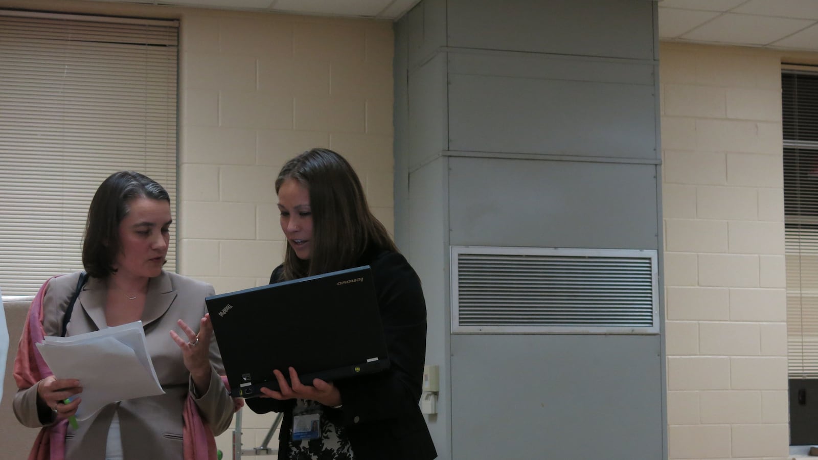Board member Amy Frogge (left) and an ASD official discuss data on the sidelines of the meeting.