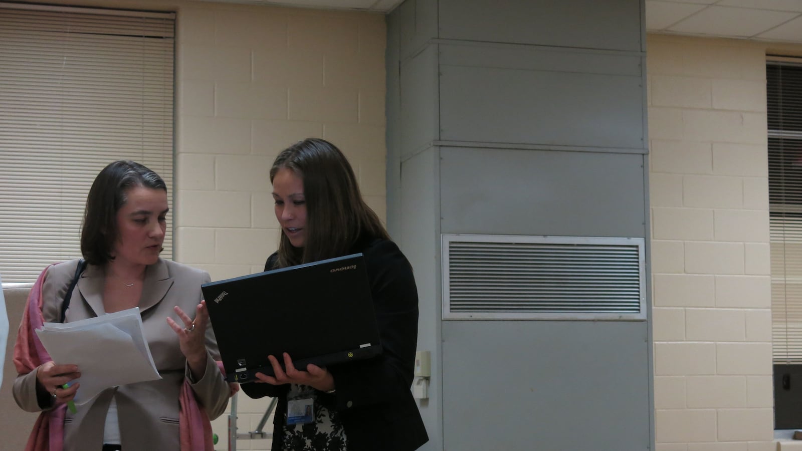 Board member Amy Frogge (left) and an ASD official discuss data on the sidelines of the meeting.