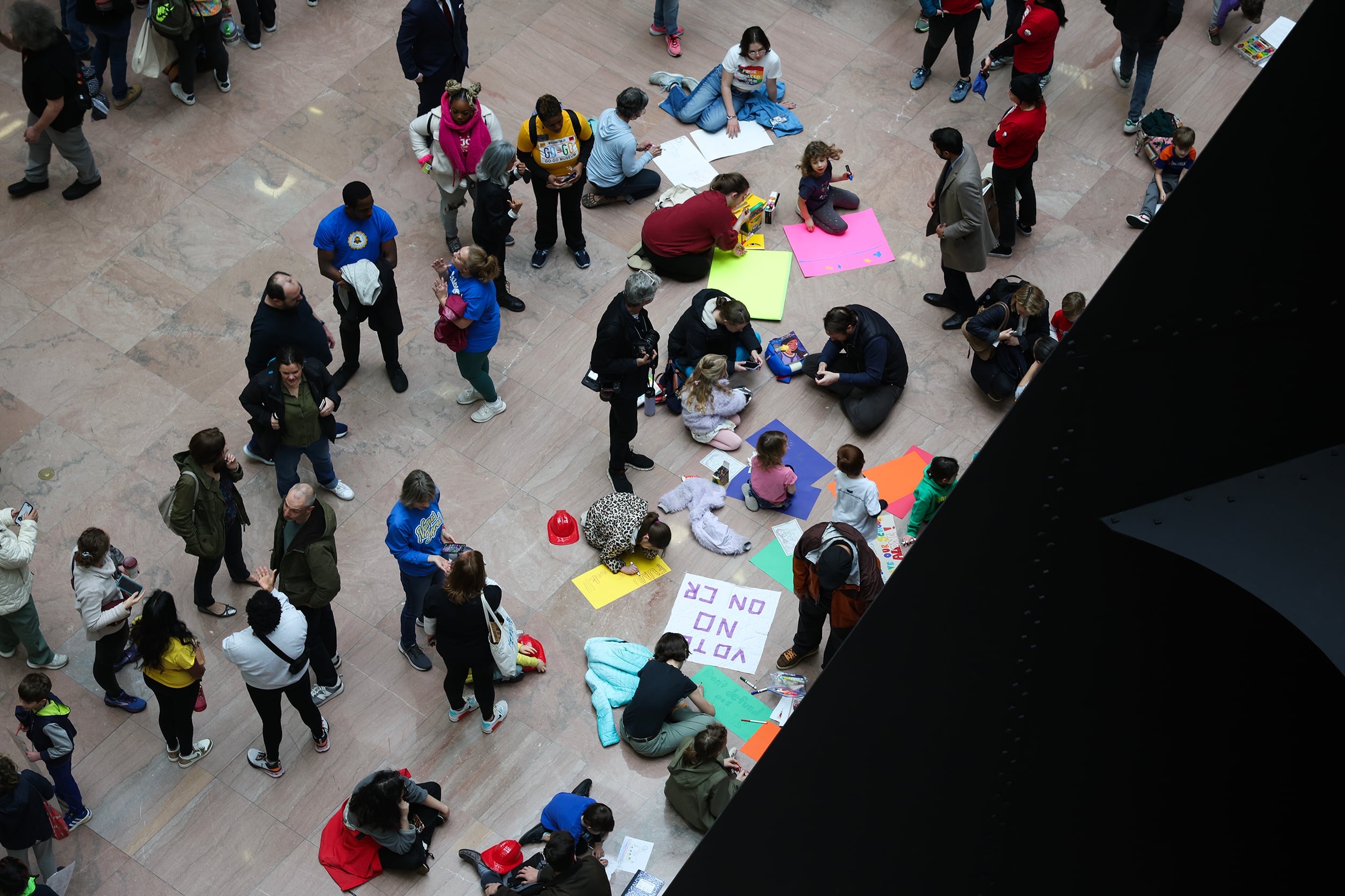 A bird's eye view of a large group of people rallying together with signs.