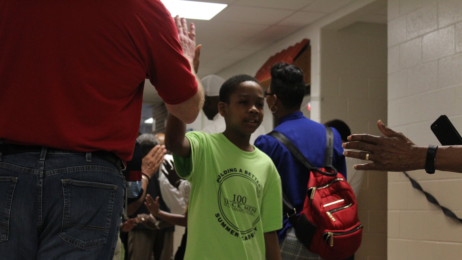 Community members and organizers with the 100 Black Men of Indianapolis' Summer Academy welcome a student with a high-five rally.