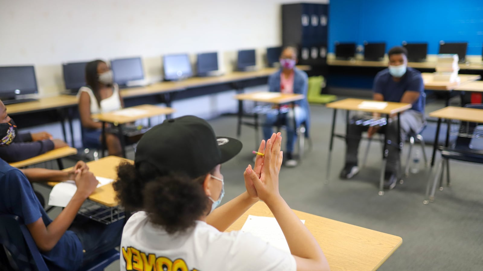 Students wearing masks participate in a discussion in school.