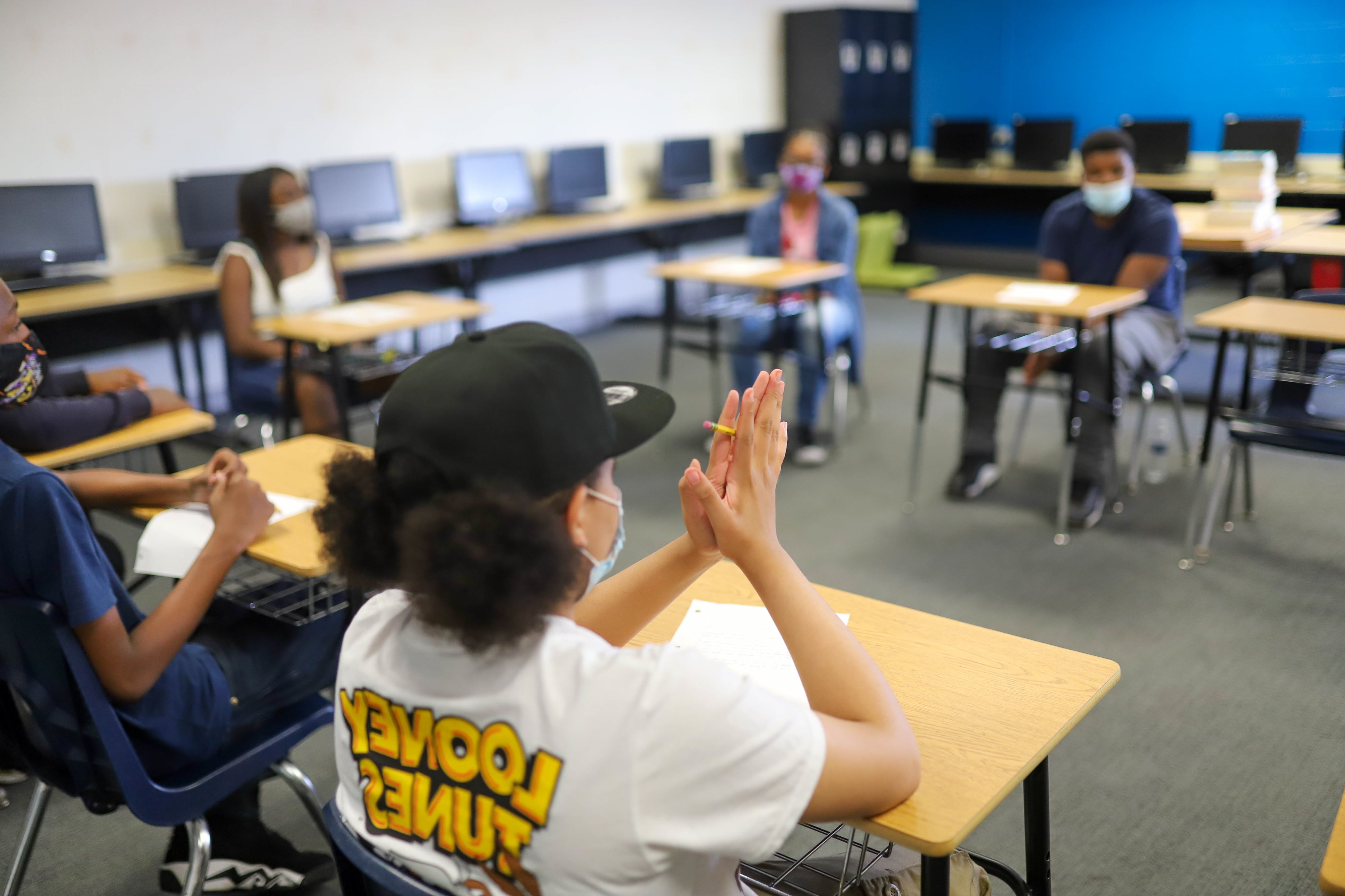 Students wearing masks participate in a discussion in school.
