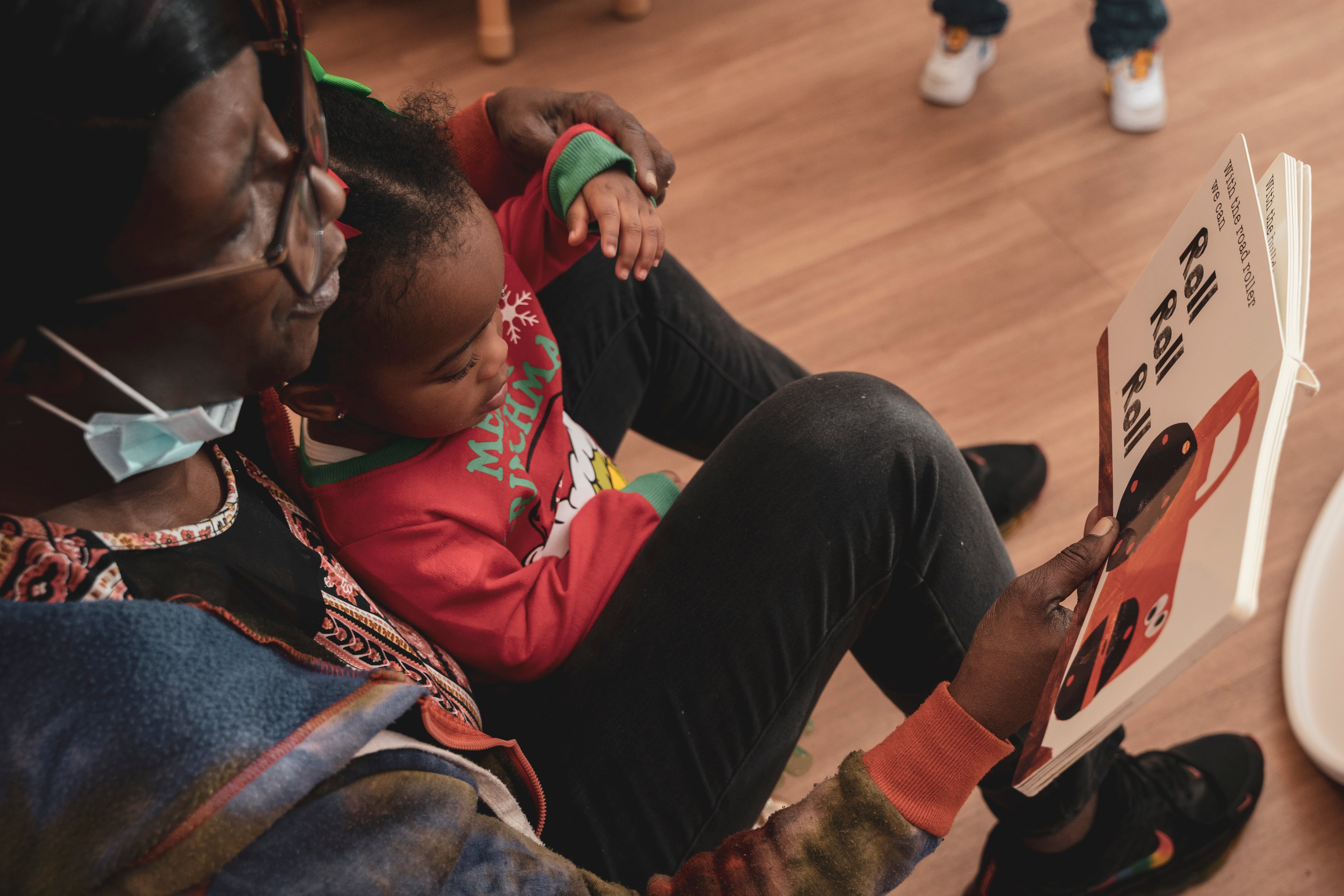 A teacher reads a book to a young student.