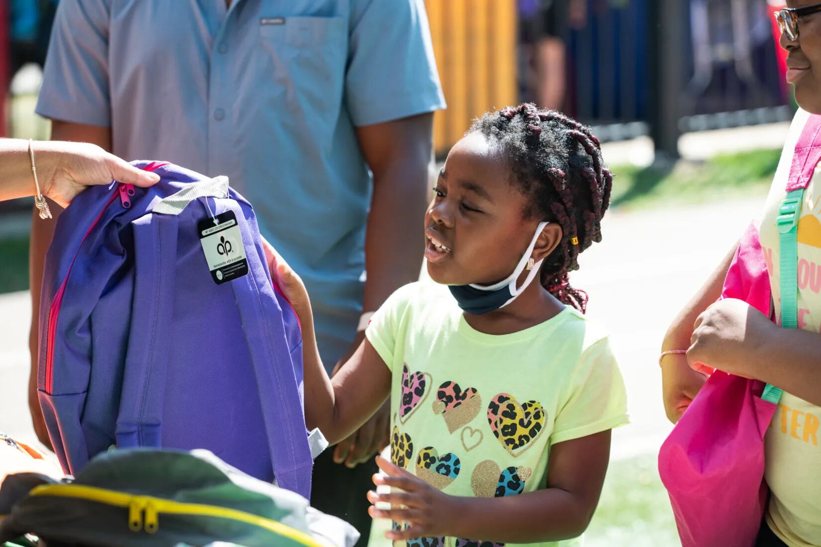 A young girl picks out a new purple backpack for the school year.