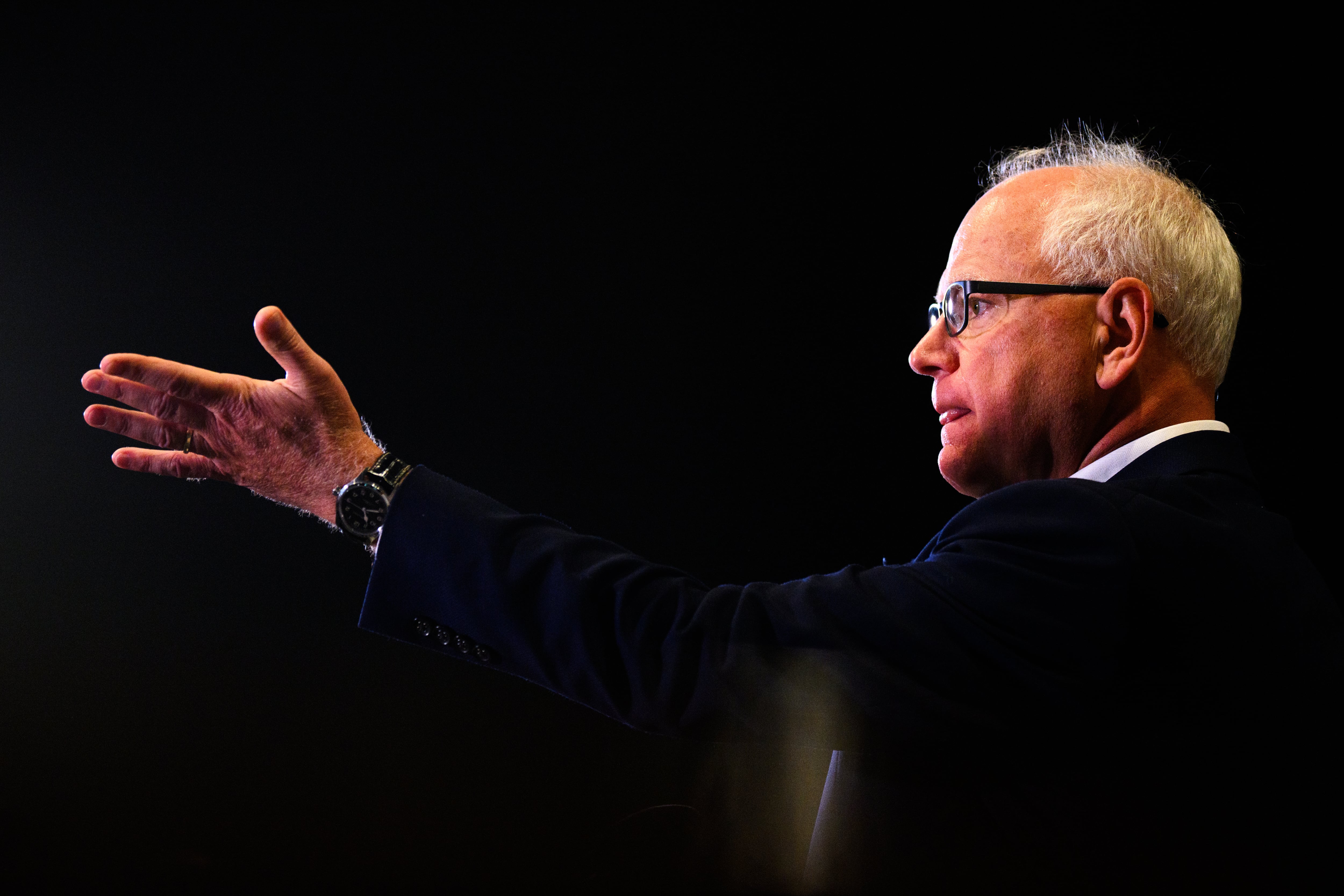 Photo of Tim Walz, seen from the side, wearing a white shirt and a suit jacket.