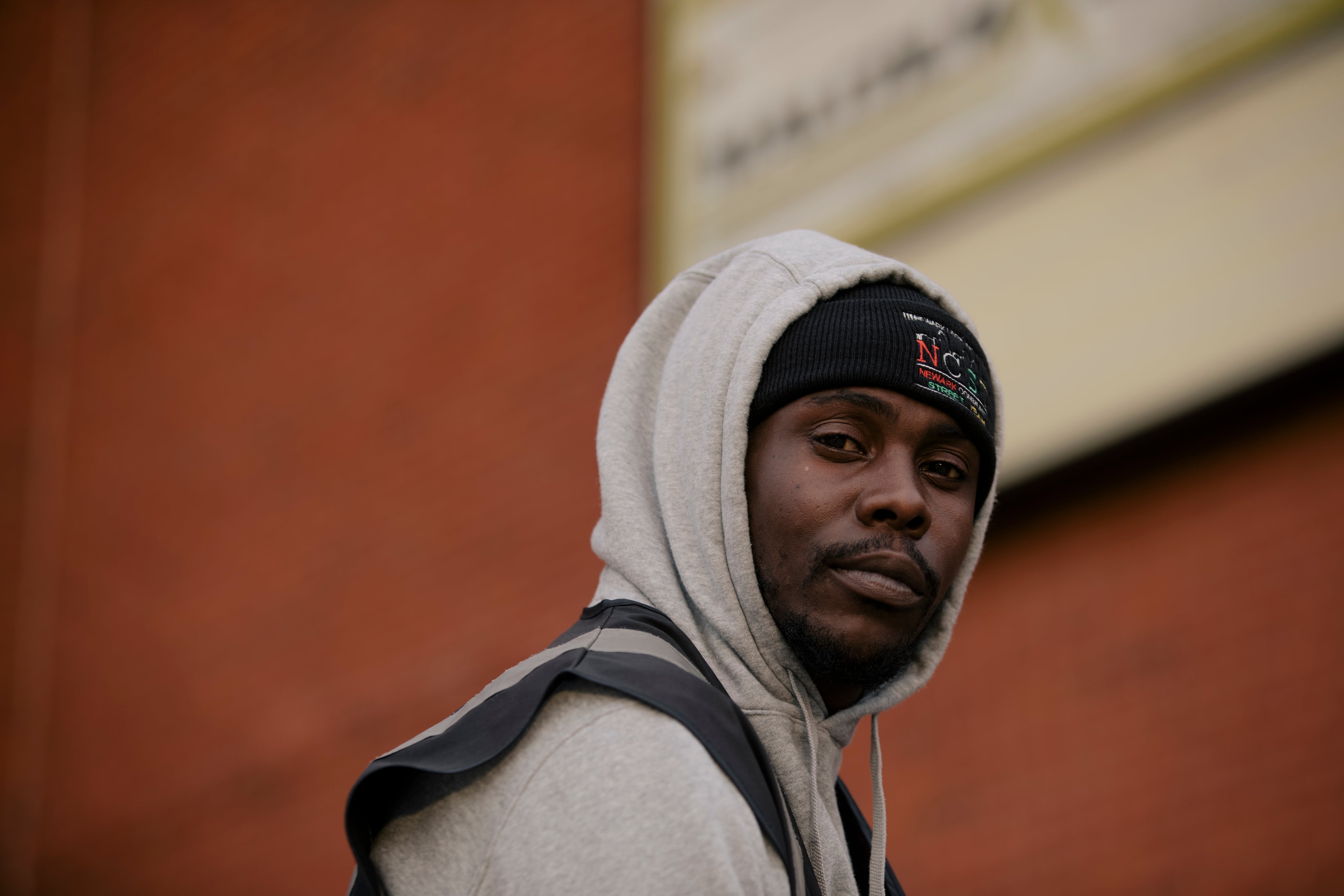 A man wearing a hoodie stares into the camera.