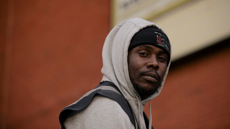 A man wearing a hoodie stares into the camera.
