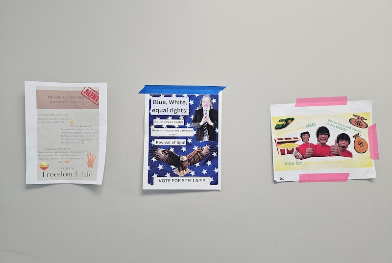 Three political posters hang on a grey wall.
