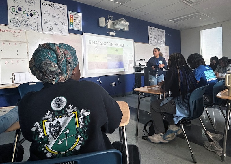 A teacher and a room full of high school students in a classroom.