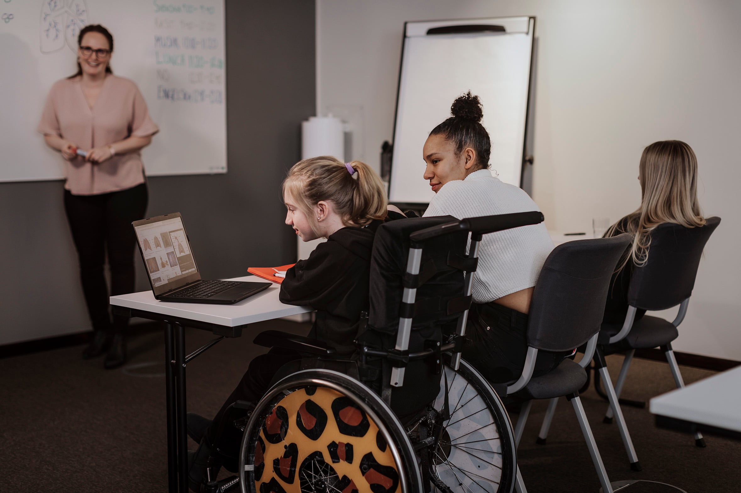 A girl in a wheelchair sits at a table.