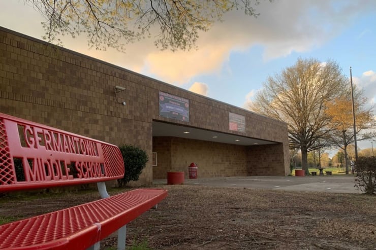An empty bench, bearing the Germantown Middle School name, sits outside of a school building.