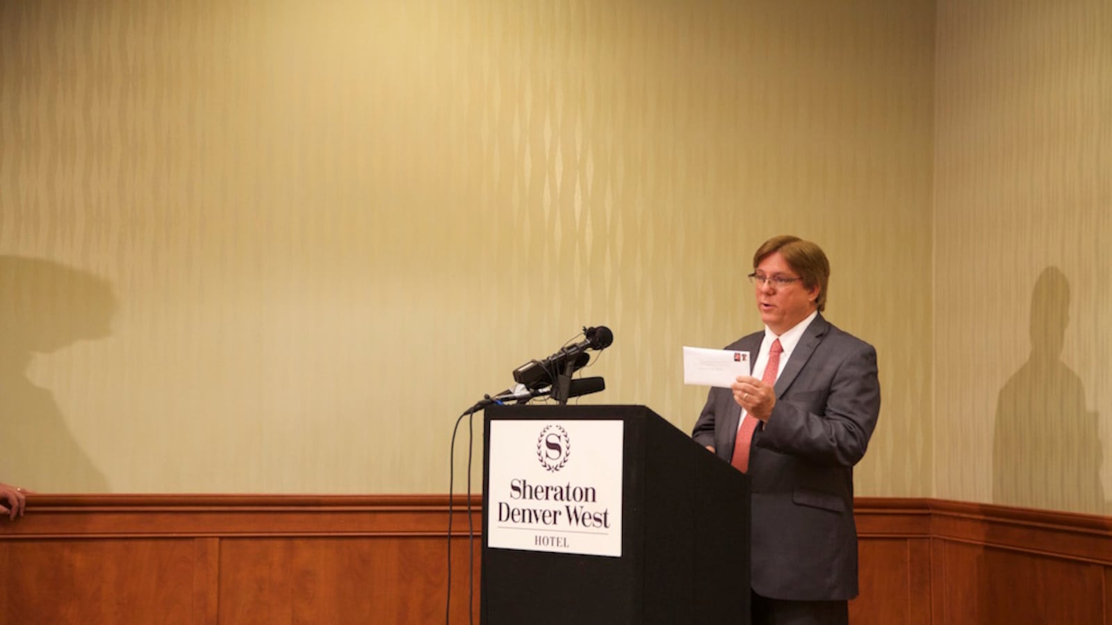 Jefferson County school board president and recall target hold an envelope containing a request for an advisory opinion from the Colorado Independent Ethics Commission.