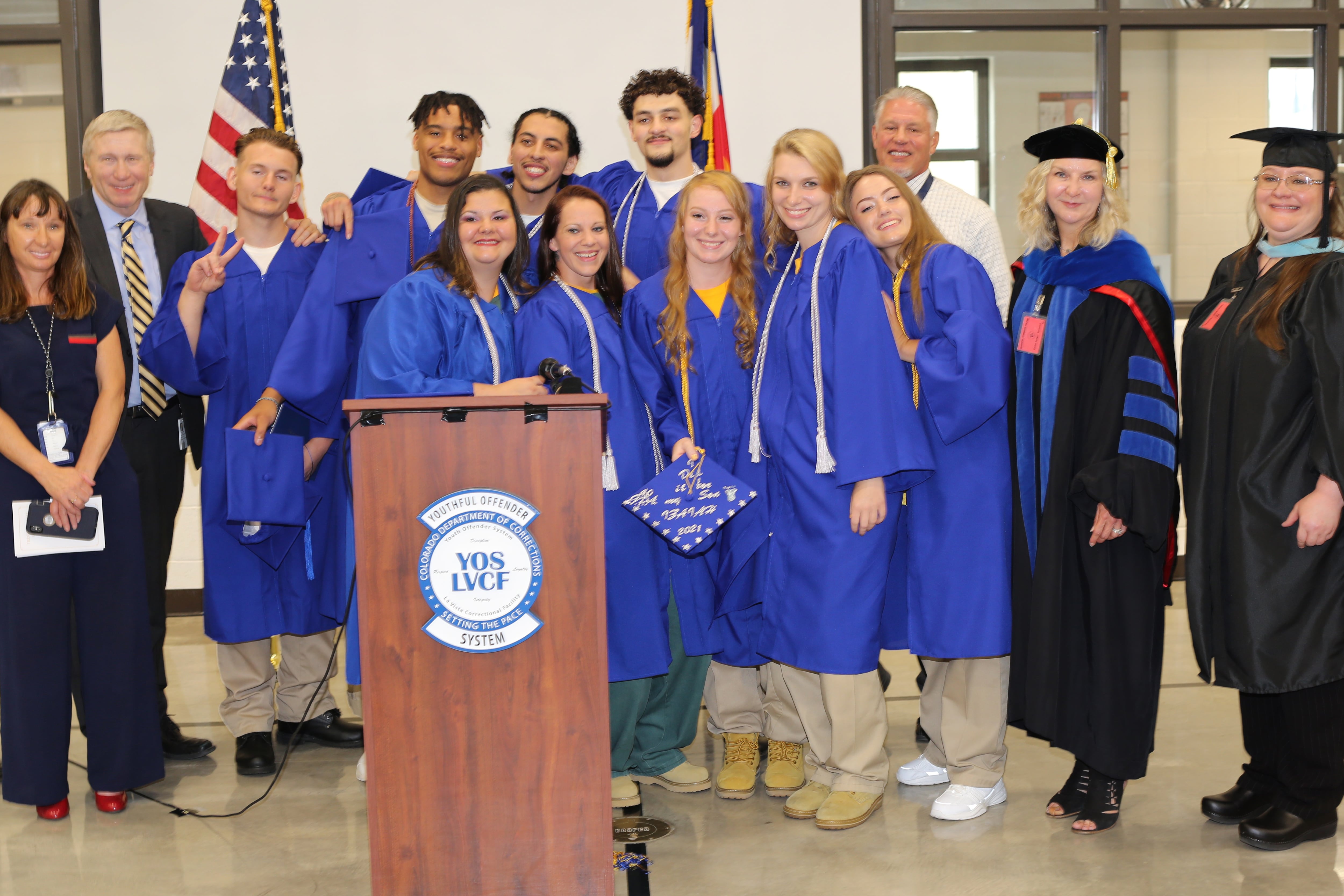 Students in blue caps and gowns and teachers in ceremonial graduation clothes pose for a picture.